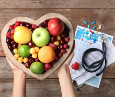 Female doctor holding plate with fresh fruits over wooden table,