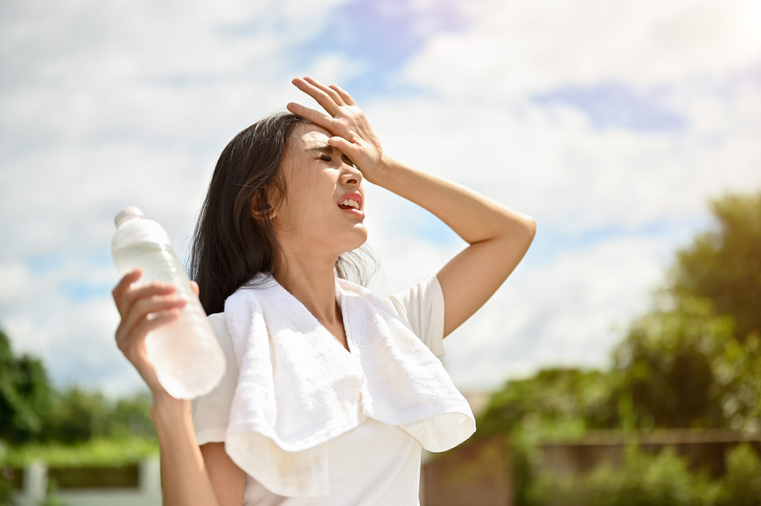 A distressed woman holding a water bottle sweats in midday heat