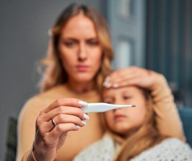 A worried mother holds a thermometer near her sick child