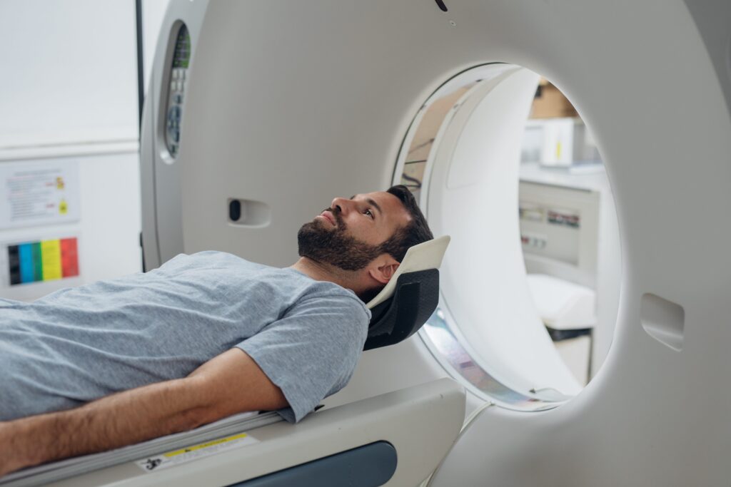 Patient positioned on CT scanner bed in medical imaging room.